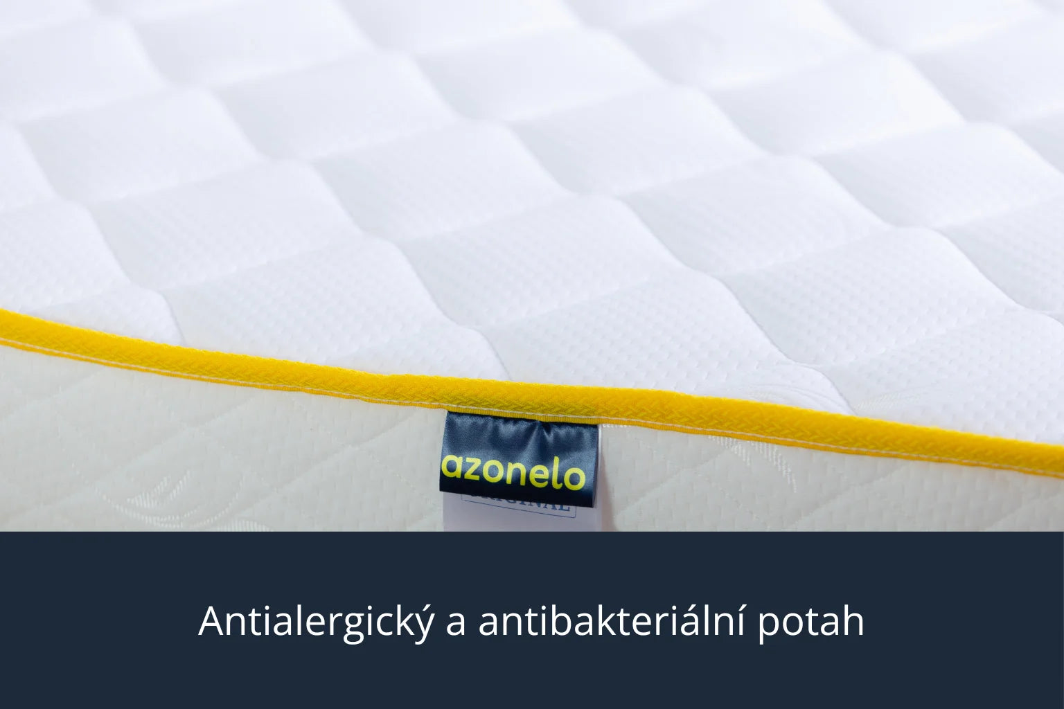 Detailní záběr na čistý bílý potah s moderním žlutým lemováním a látkovou nášivkou s logem Azonelo. Materiál je měkký na dotek, prodyšný a upravený tak, aby byl vhodný pro alergiky.