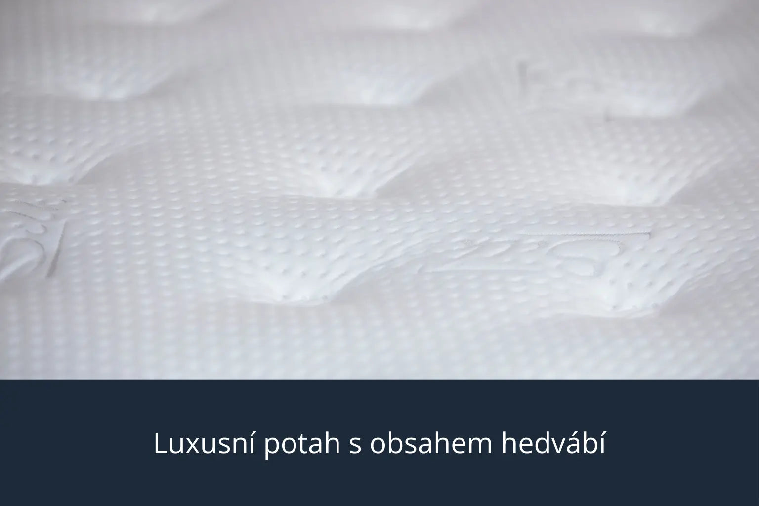 Detailní záběr na luxusní potah s obsahem hedvábí na matraci Azonelo Cloud, který ukazuje jemnou bílou texturu látky.