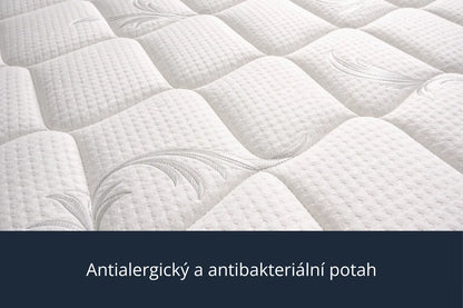 Detailní záběr na bílý, prošívaný potah matrace s textem „Antialergický a antibakteriální potah“