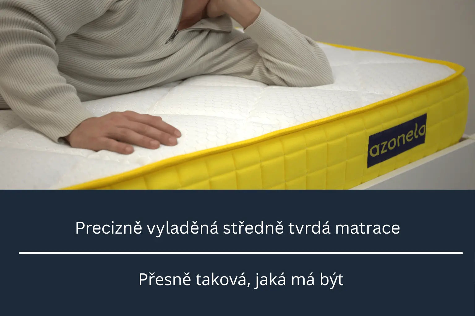 Detail matrace Azonelo s mužem ve svetru, který testuje její pohodlí. Obrázek jasně označuje, že se jedná o středně tvrdou matraci, která je ideální pro většinu uživatelů, s vizuální stupnicí tvrdosti od měkké po tvrdou.